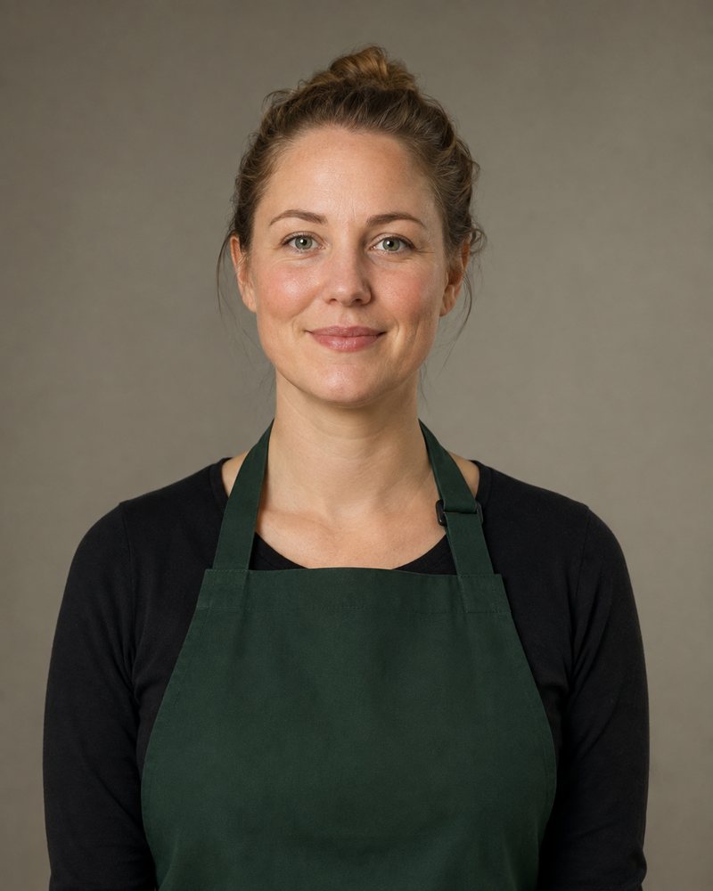 Portret van een vrouw van ongeveer 35 met haar in een knot en een donkergroene schort