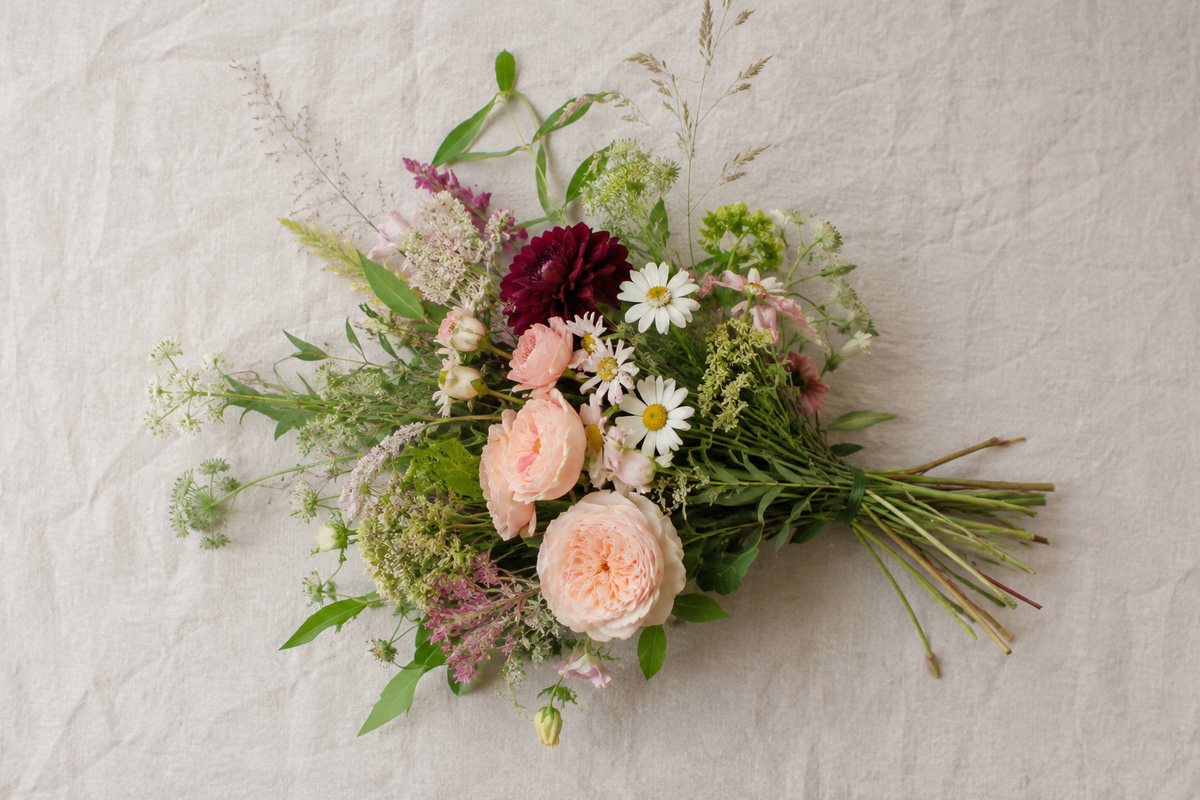 Los gebonden boeket met roze en witte tuinbloemen op een lichte linnen ondergrond